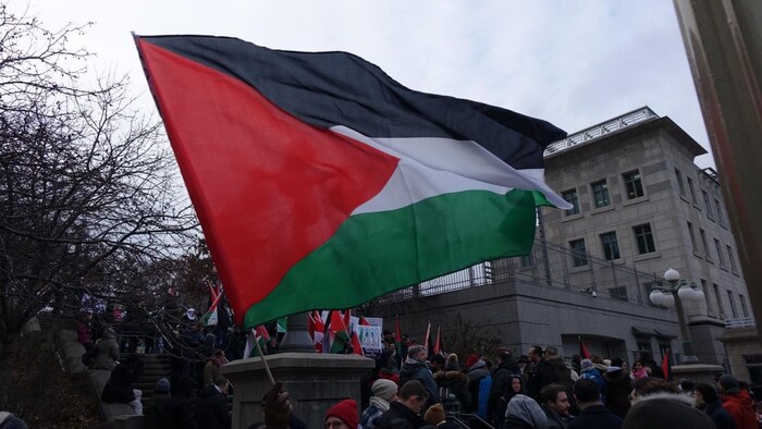 Un drapeau palestinien qui flotte au vent devant des manifestants réunis près de l'ambassade américaine.
