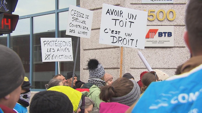 Des gens qui tiennent des pancartes devant le bureau de Jean Boulet à Trois-Rivières.