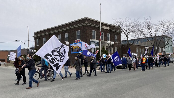 Des gens marchent en tenant des drapeaux de syndicats.