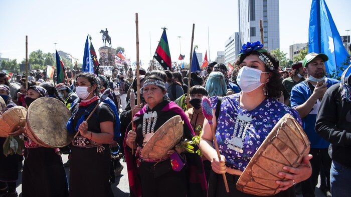 Des femmes autochtones avec des tambours et des masques dans une manifestation. 