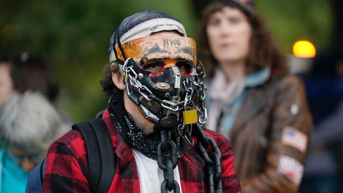 Un homme porte un masque fait de chaînes métalliques.
