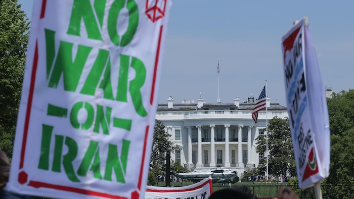 La pancarte d'un manifestant indique « Pas de guerre en Iran » lors du 1er mai à Washington D.C., devant la Maison-Blanche.