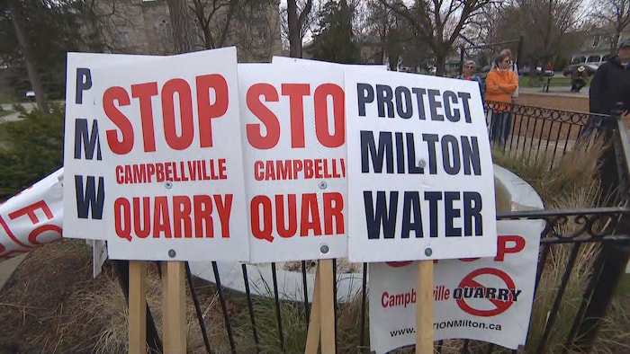 Des pancartes avec les mots : Arrêtez la carrière de Campbellville et Protégez l'eau de Milton.