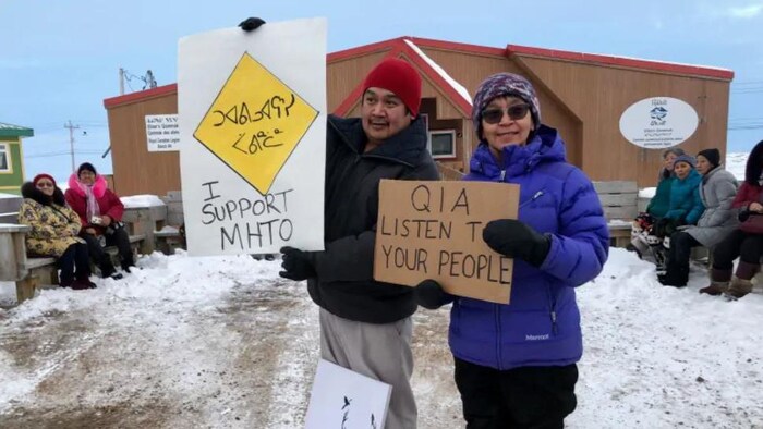 Deux manifestants tiennent des pancartes.