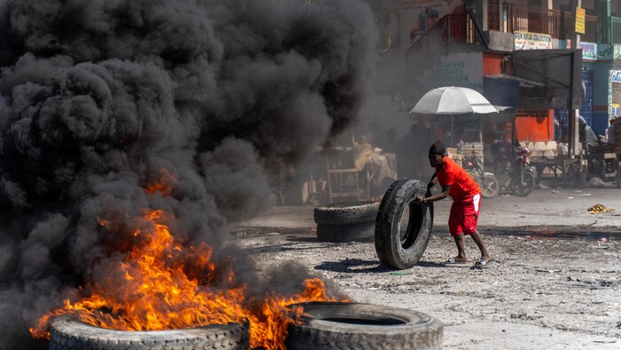 Un homme fait rouler un pneu vers des flammes.