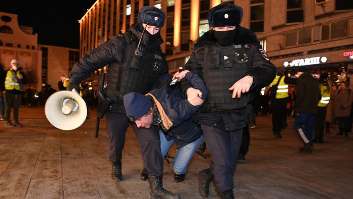 Un homme se fait arrêter par deux policiers.