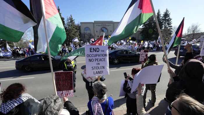 Des manifestants pro-Israéliens et propalestiniens avec des drapeaux des deux côtés d'une rue, devant une synagogue.