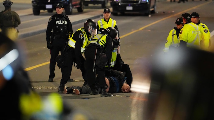 Un homme, au sol, arrêté par quelques policiers.