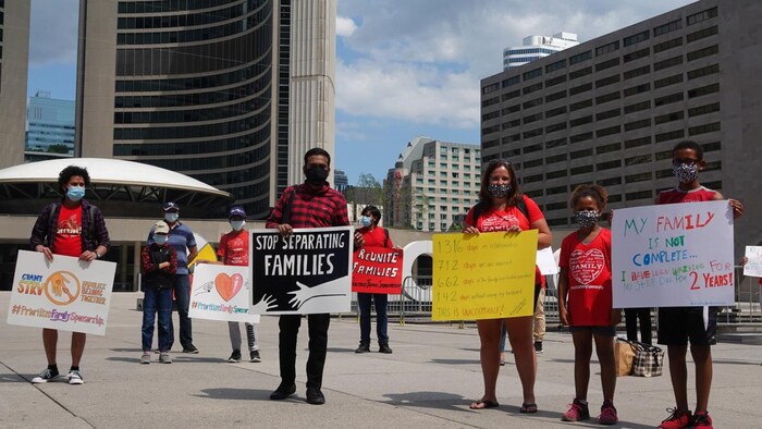 Des manifestants avec des pancartes devant l'hôtel de ville de Toronto.