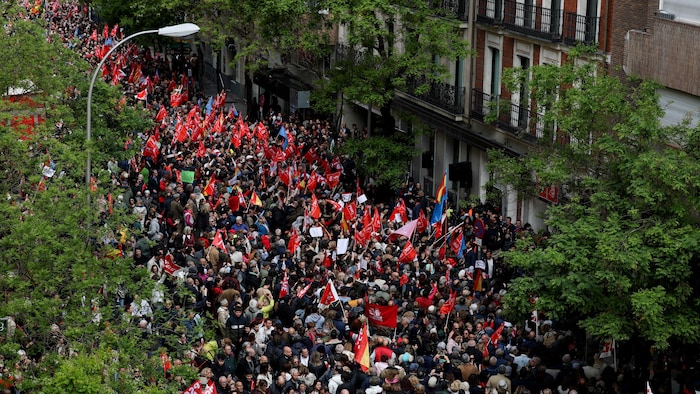 Devant un immeuble, des centaines, voire des milliers de manifestants sont rassemblés, plusieurs tenant un drapeau du Parti socialiste ou un drapeau espagnol.