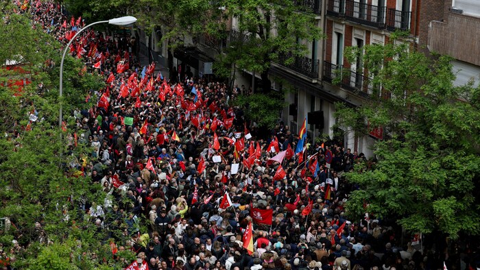 Devant un immeuble, des centaines, voire des milliers de manifestants sont rassemblés, plusieurs tenant un drapeau du Parti socialiste ou un drapeau espagnol.