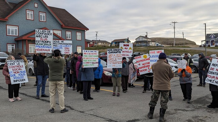 Des manifestants avec des pancartes devant des bureaux.