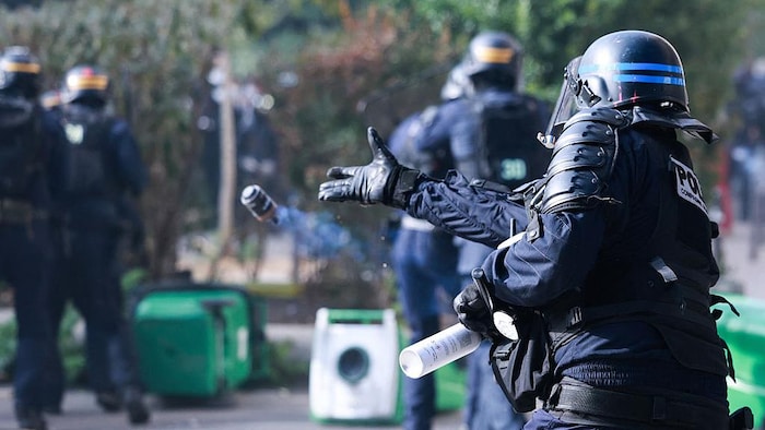 Un policier lance une grenade de dispersion lors d’une manifestation de lycéens, à Paris.