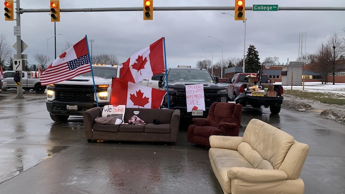 كنبات وشاحنات صغيرة وأعلام كندية وأميركية وسط الشارع.