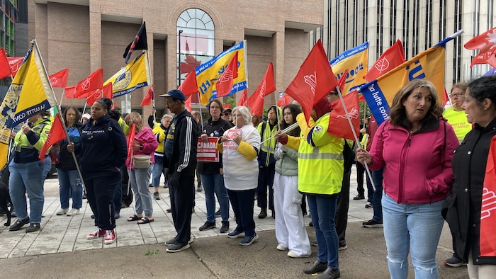 Des manifestants brandissent des drapeaux du Syndicat des travailleurs et travailleuses des postes.