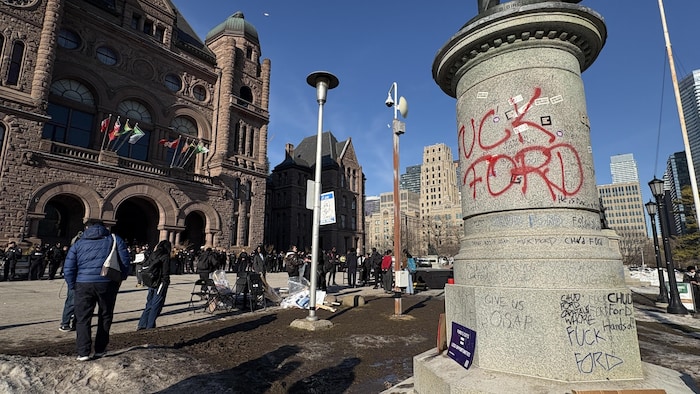 Le pied d’une statue devant Queen’s Park à Toronto a été vandalisé et marqué de graffitis injurieux envers Doug Ford lors de la manifestation étudiante du 4 mars 2026.