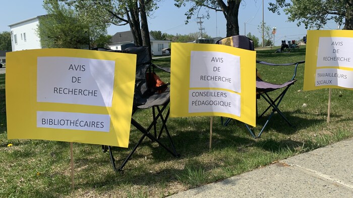 Trois affiches et deux chaises pliantes. Les affiches indiquent «Avis de recherche» pour des bibliothécaires, des conseillers pédagogiques et des travailleurs sociaux.