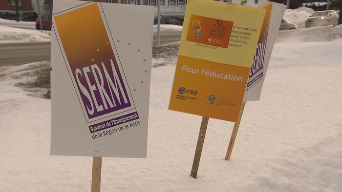 Des pancartes du Syndicat de l'enseignement de la région de la Mitis sont plantées dans la neige.