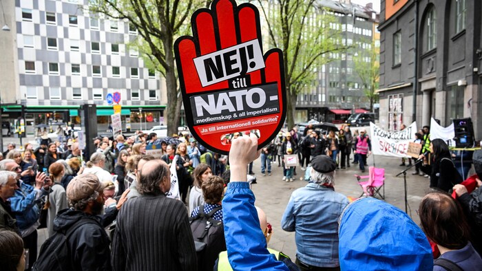 Un manifestant au milieu d'une foule brandit une pancarte contre l'adhésion de la Suède à l'OTAN.