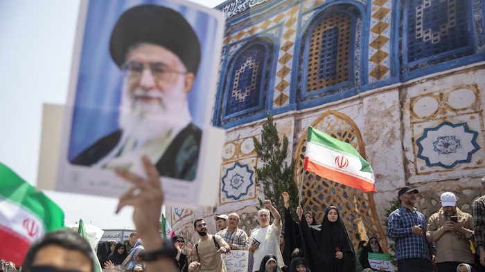 Protesters in Tehran brandish Iranian flags and a portrait of the Iranian Supreme Guide.