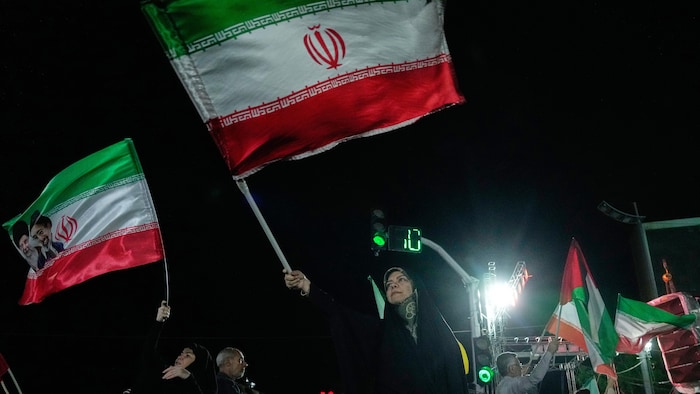 Des manifestants pro-gouvernementaux brandissent des drapeaux iraniens.