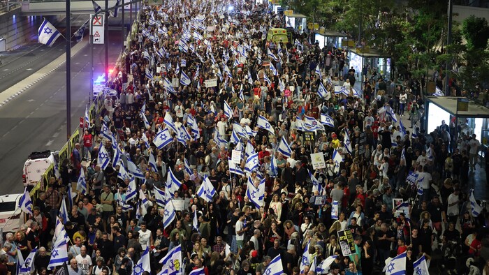 Des milliers de personnes sont entassées dans une rue. Elles portent des drapeaux d'Israël et des pancartes.