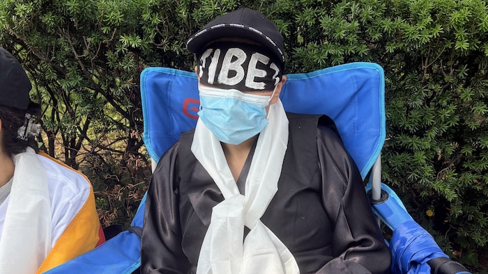 Un manifestant devant le consulat de la Chine à Toronto portant un bandeau noir avec l’inscription « Tibet » en lettres blanches sur les yeux.