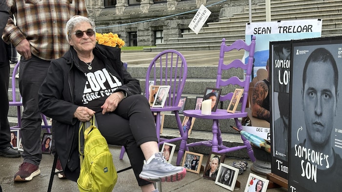 Leslie McBain assise sur une chaise avec des photos de personnes autour d'elle.