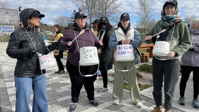 Quatre femmes tapent dans des percussions avec des slogans inscrits.