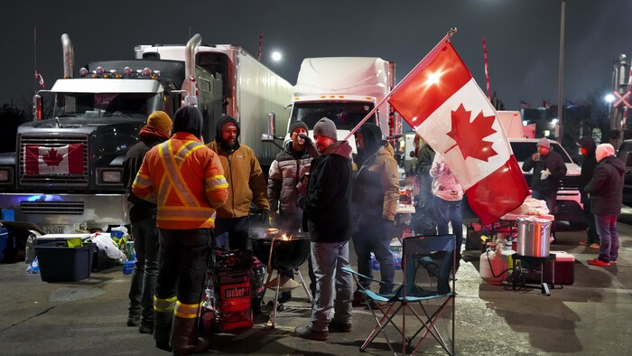 Des camionneurs réunis autour d'un barbecue, la nuit tombée.