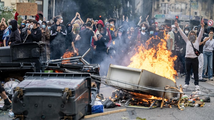 Des manifestants se tiennent derrière des déchets en feu.