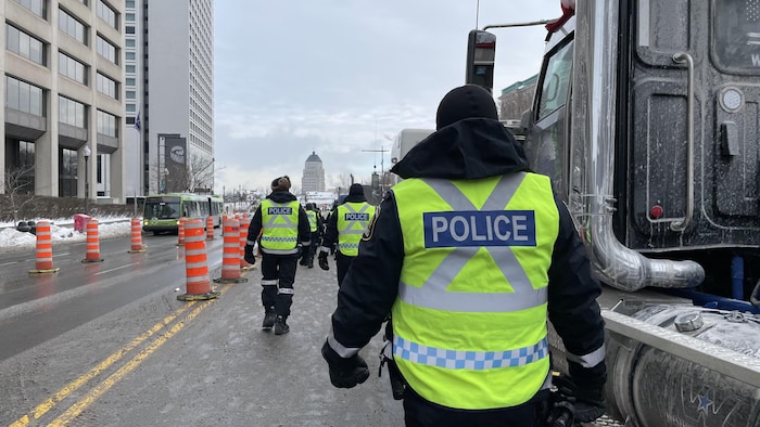 Des policiers à proximité des poids lourds stationnés sur le boulevard René-Lévesque dimanche matin.