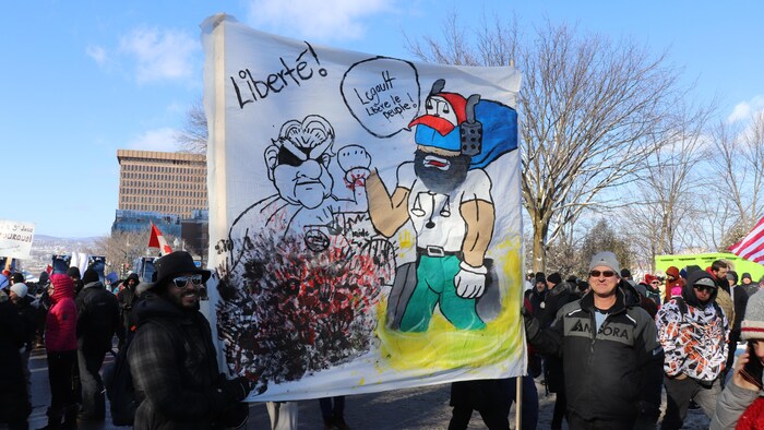 Une affiche mettant en vedette un superhéros camionneur demandant à François Legault de "libérer le peuple".