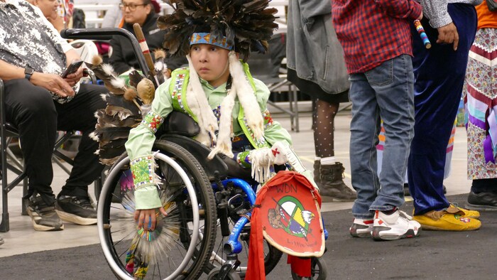 Un enfant en chaise roulante portant ses regalia.