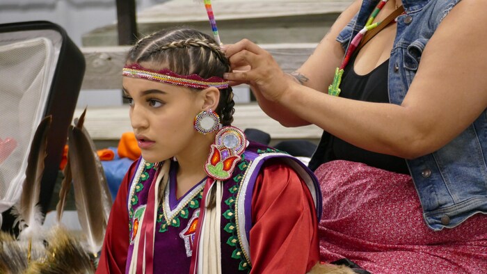 Une jeune danseuse autochtone se prépare à la Grande entrée. 
