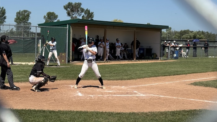 Une personne sur un terrain de baseball s'apprêtant à frapper la balle.