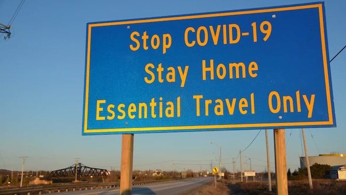 Une pancarte qui dit de rester chez soi et de voyager seulement pour des raisons essentielles
