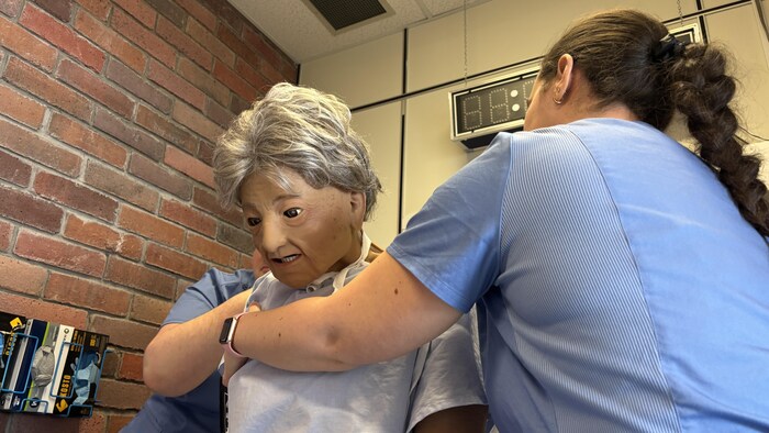Des étudiants en soins infirmiers manipulent un mannequin réaliste.