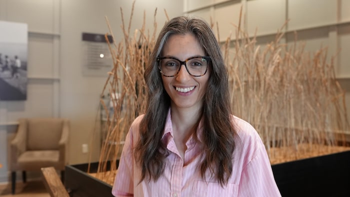 Portrait de Héloïse Tanguay-Beaumont est la directrice générale du Manoir Belle Plage, elle porte une chemise et est debout devant des graminés.