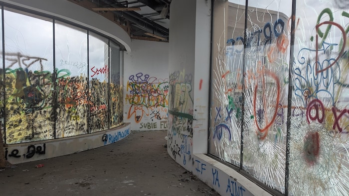 Un couloir ondulé est couvert de graffitis.