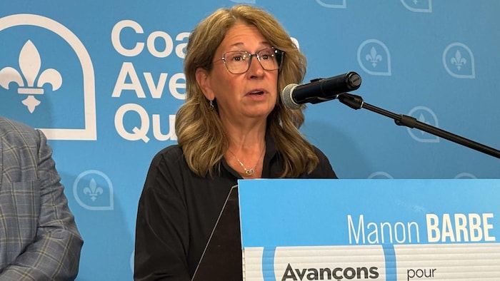 Manon Barbe parle au micro, debout derrière un lutrin.