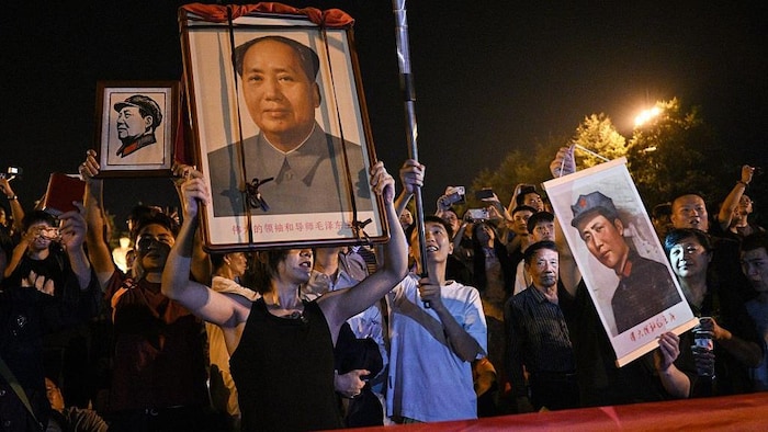 Des gens tiennent des portraits de Mao lors d'une cérémonie.