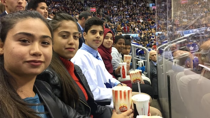 Al Mouktaran is pictured here in red in the middle with her friends at a Leafs game. (Supplied by Abrar Al Mouktaran)