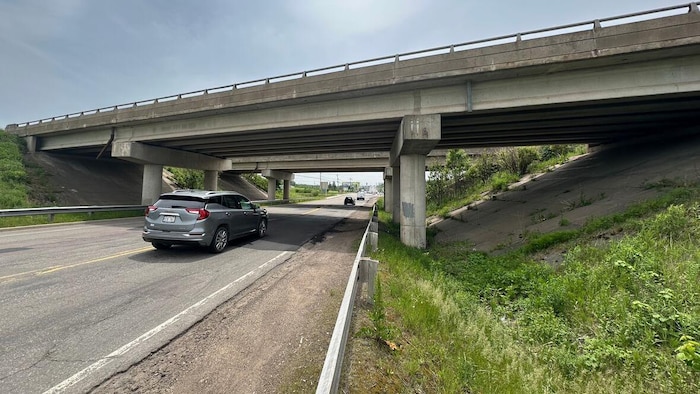 La route sous le viaduc de l'autoroute qui a seulement un accotement en gravier.