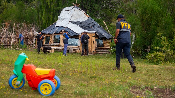 Des policiers s'approchent d'une hutte.