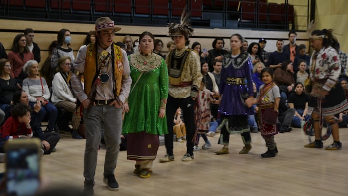 Des danseurs autochtones portent leur regalia lors d'un pow-wow auquel sont invitées plusieurs personnes.