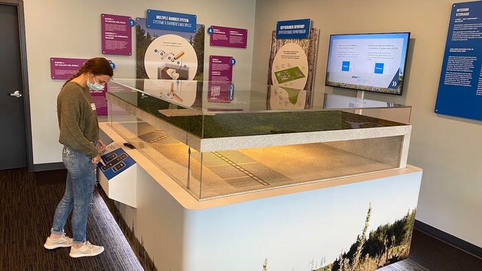 Une jeune femme regarde la maquette de dépôt géologique en profondeur.