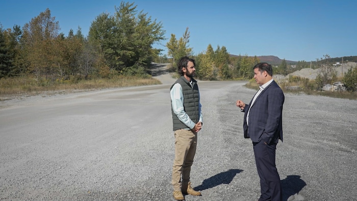 Deux hommes discutent dans un terrain vague.