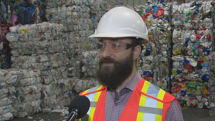 Marc-André Chiasson en entrevue. Derrière lui se trouve du plastique qui a été empaqueté en vue d'être recyclé.