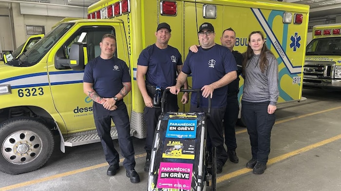 Marc-André Provost pose avec quatre personnes devant une ambulance, à l'intérieur d'une caserne.